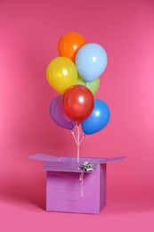 Photo of Gift box with bright air balloons on color background