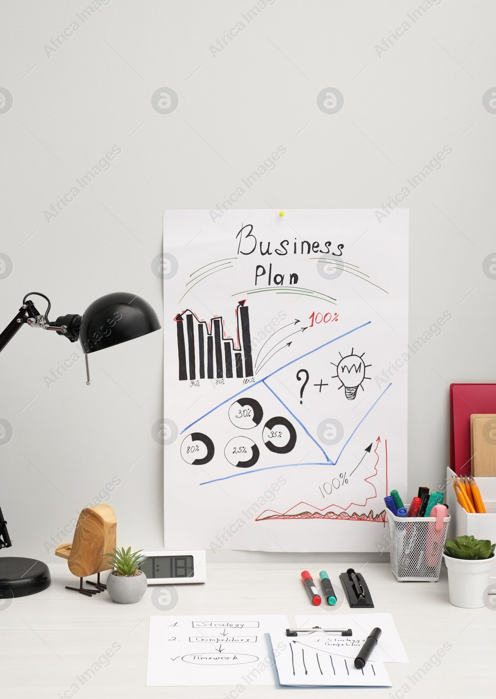 Photo of Business process planning and optimization. Workplace with plan, lamp, notebook and stationery on white wooden table