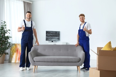 Moving service employees with sofa in room