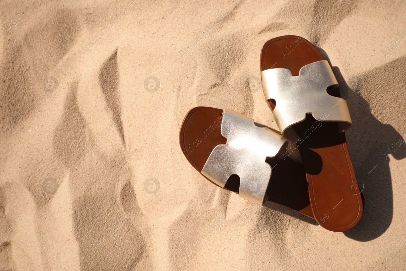 Photo of Flip flops on sandy sea shore, top view with space for text. Beach accessory