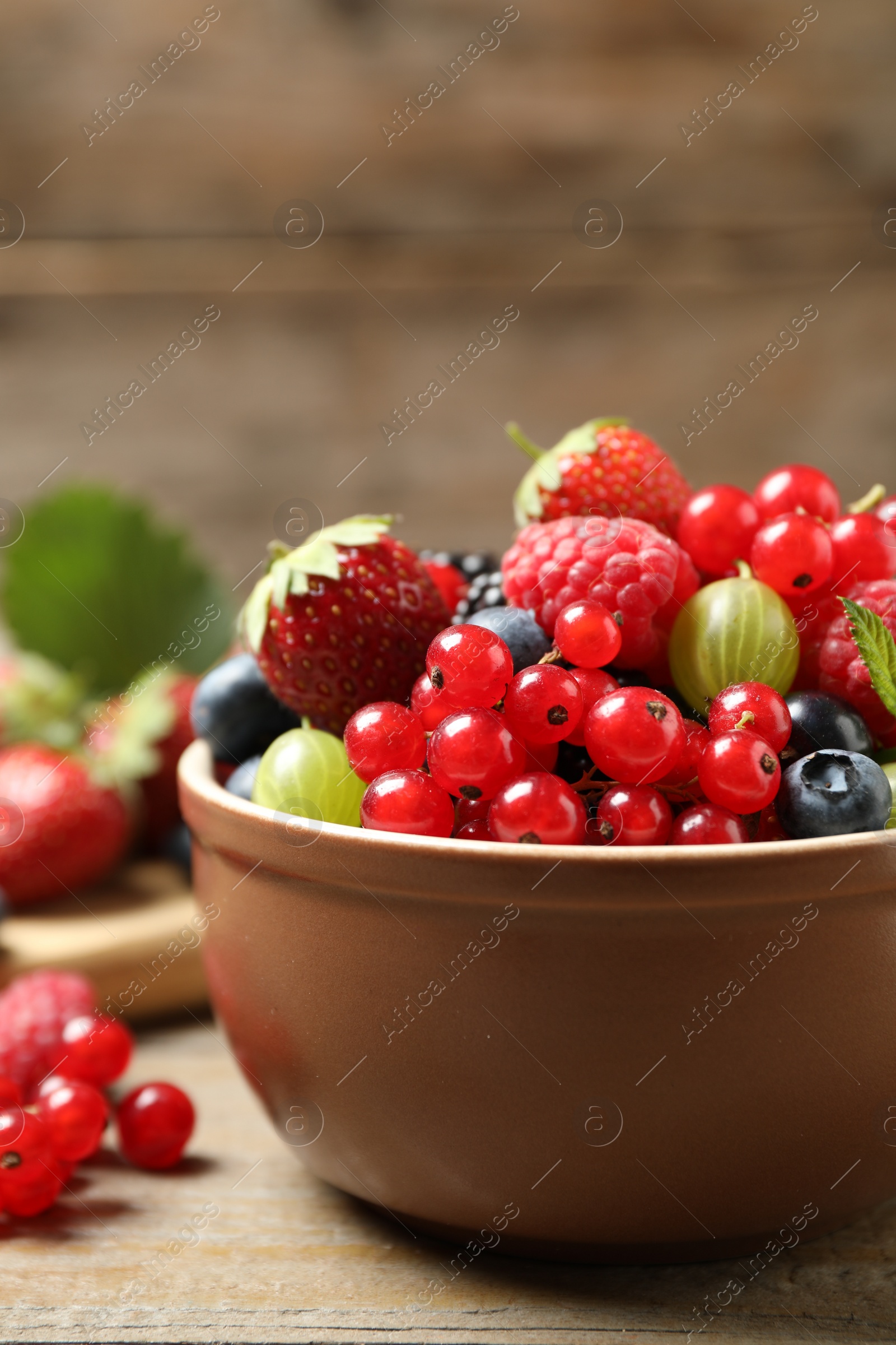 Photo of Mix of different fresh berries in bowl on wooden table