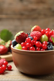 Photo of Mix of different fresh berries in bowl on wooden table