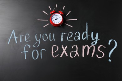 Photo of Blackboard with phrase Are You Ready For Exams and alarm clock as background, top view