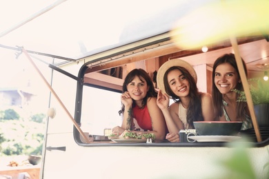 Photo of Happy young women in trailer, view from outside. Camping vacation
