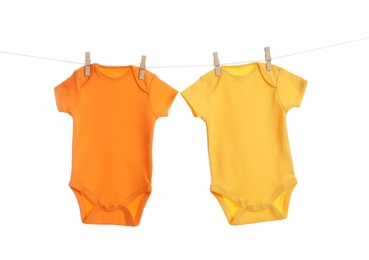 Photo of Colorful baby onesies hanging on clothes line against white background. Laundry day