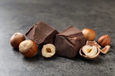 Photo of Delicious chocolate chunks and hazelnuts on grey table