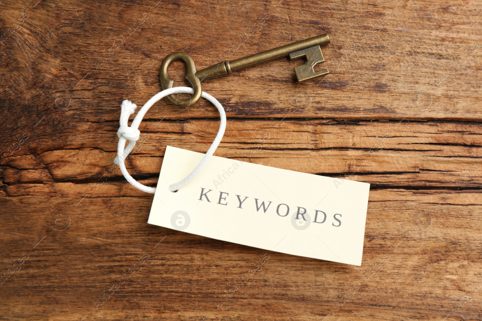 Photo of Vintage key and tag wIth word KEYWORDS on wooden table, top view