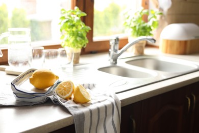 Fresh ripe lemons near sink in kitchen, space for text