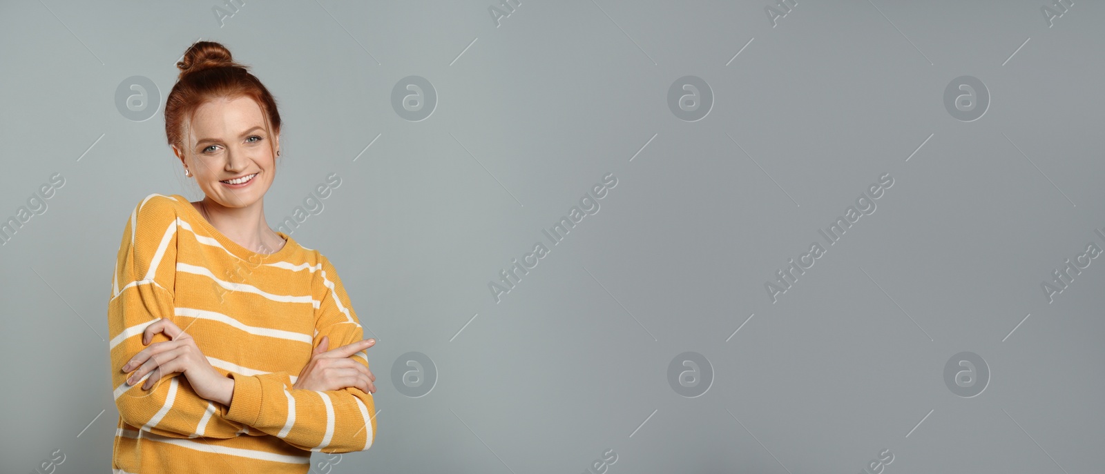 Photo of Candid portrait of happy red haired woman with charming smile on grey background, space for text