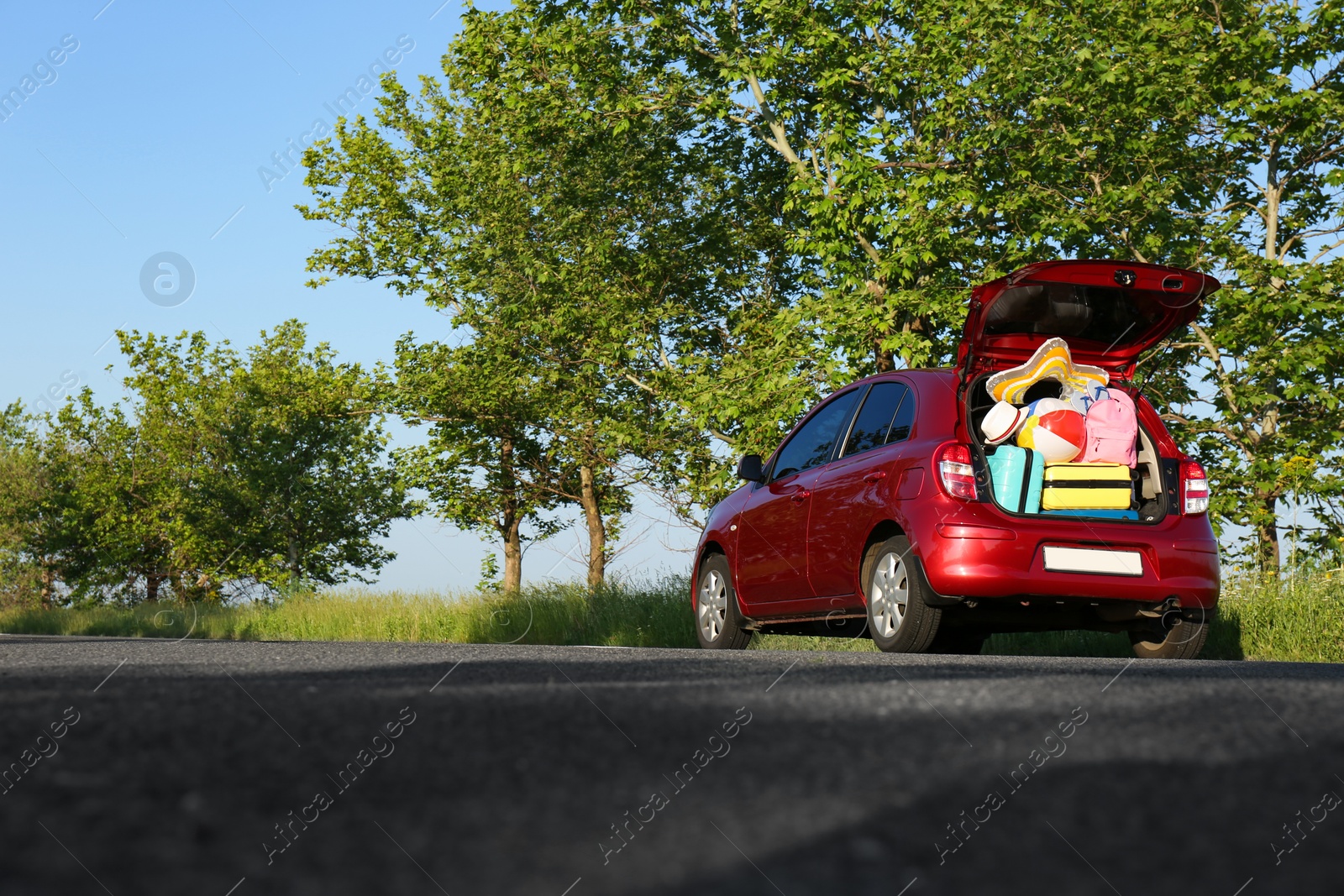 Photo of Family car with open trunk full of luggage on highway. Space for text