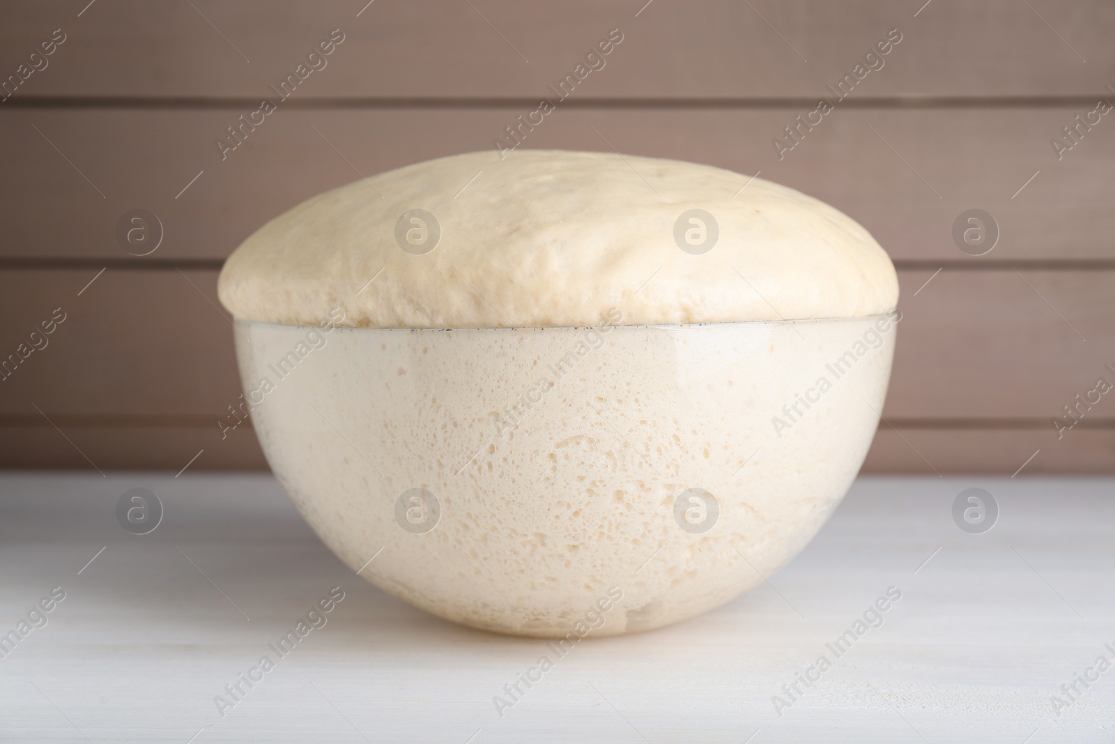 Photo of Bowl of fresh yeast dough on white wooden table