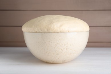 Photo of Bowl of fresh yeast dough on white wooden table