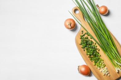Flat lay composition with fresh green onion on white wooden table. Space for text