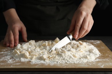 Photo of Woman making shortcrust pastry with knife at table, closeup