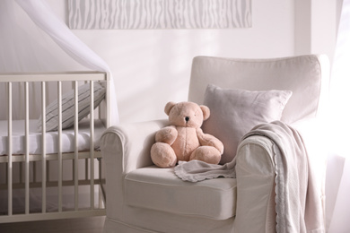 Photo of Baby room interior with comfortable crib and armchair