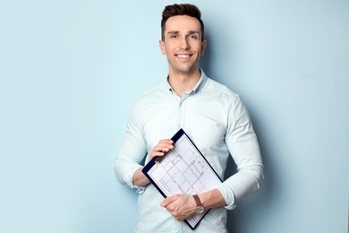 Photo of Male real estate agent with clipboard on light background