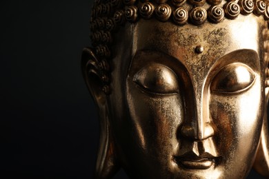 Beautiful golden Buddha sculpture on black background, closeup. Space for text