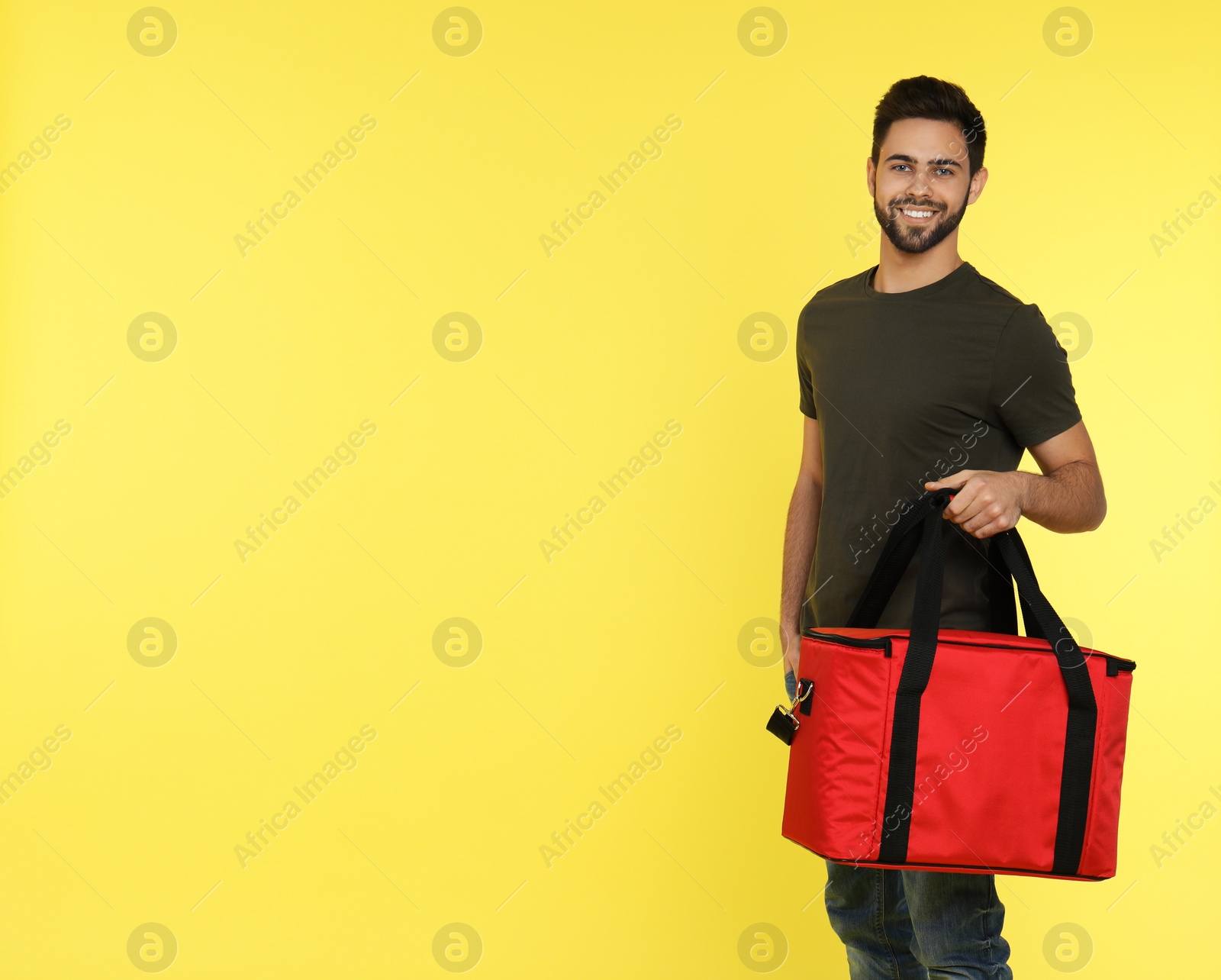 Photo of Young courier with thermo bag on color background, space for text. Food delivery service