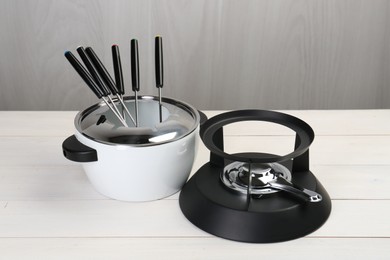 Fondue set on white wooden table. Kitchen equipment