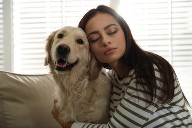 Young woman and her Golden Retriever on sofa at home. Adorable pet