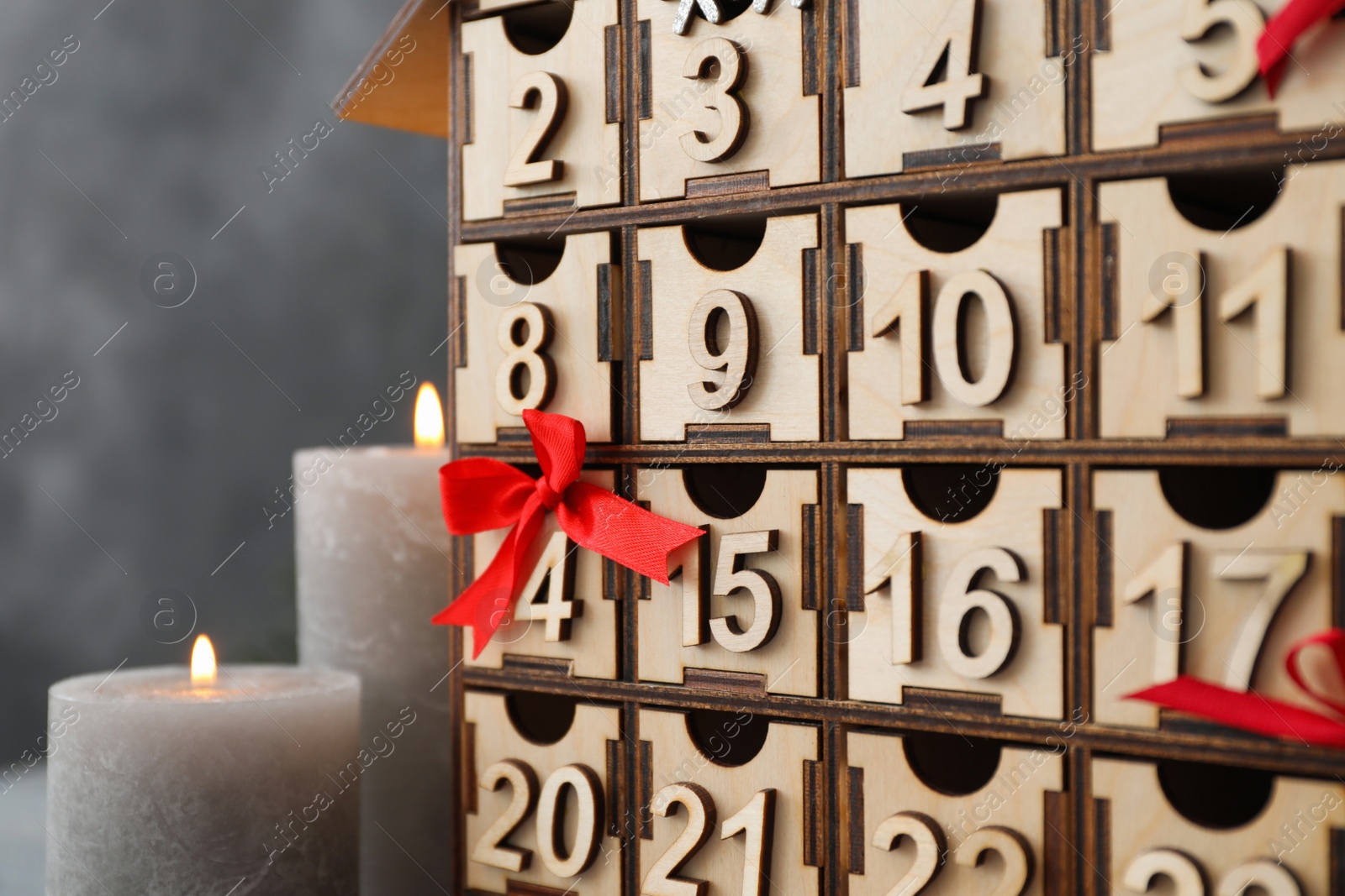 Photo of Wooden Christmas advent calendar and burning candles on grey background, closeup