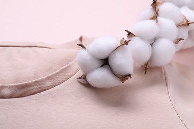 Cotton branch with fluffy flowers and t-shirt on beige background, closeup