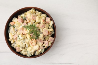 Photo of Tasty Olivier salad with boiled sausage in bowl on white wooden table, top view. Space for text