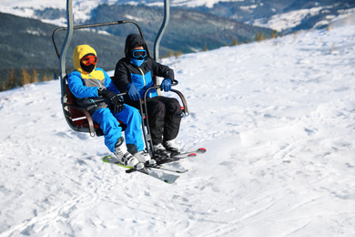 Photo of People using chairlift at mountain ski resort, space for text. Winter vacation