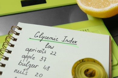 Notebook with products of low glycemic index, calculator, measuring tape and lemon, closeup