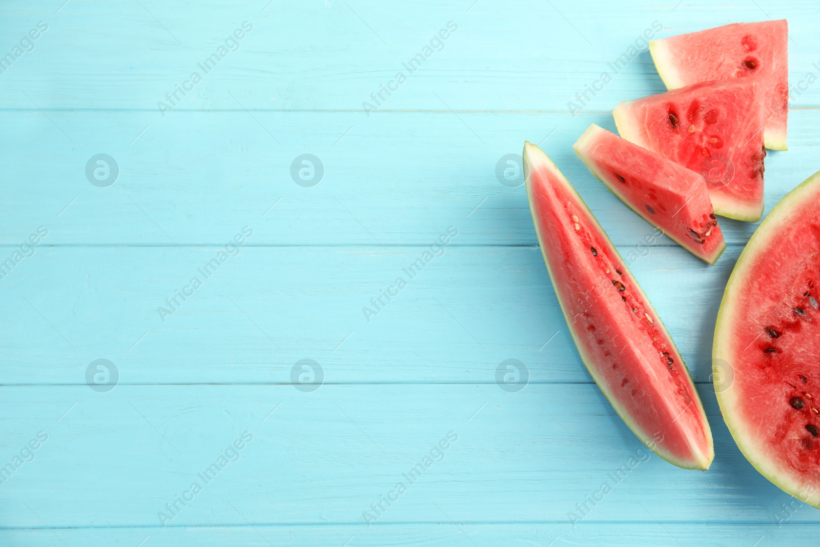 Photo of Tasty ripe cut watermelon on light blue wooden table, flat lay. Space for text