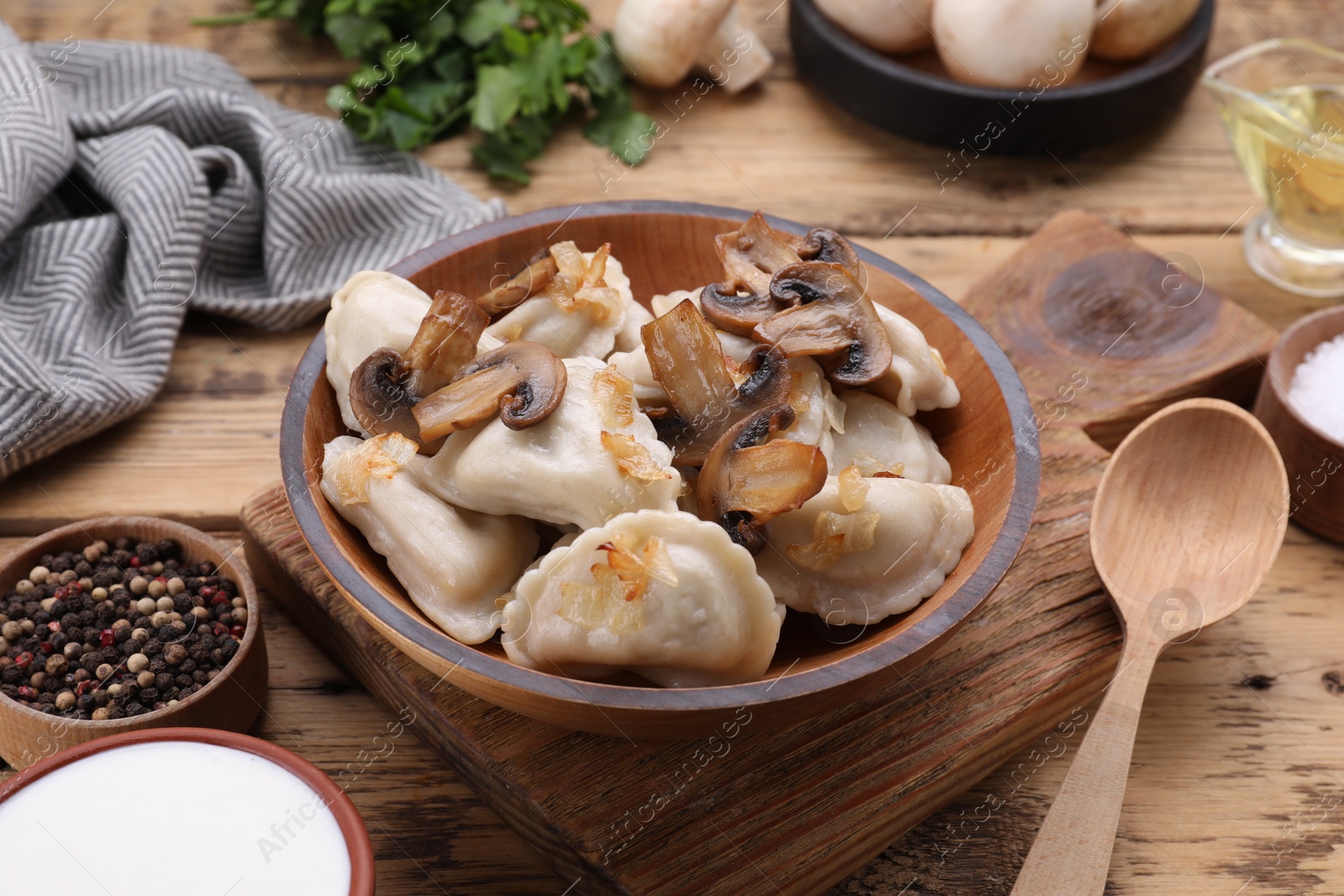 Photo of Delicious dumplings (varenyky) with potatoes, onion and mushrooms served on wooden table