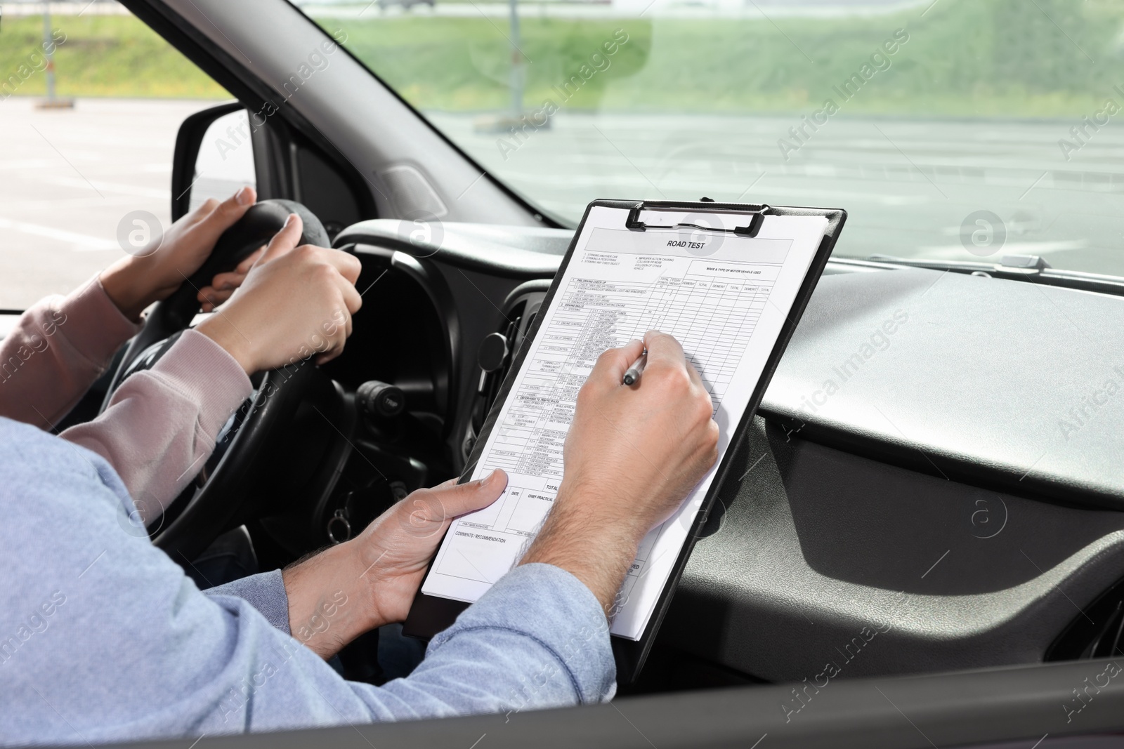 Photo of Driving school. Student passing driving test with examiner in car at parking lot, closeup