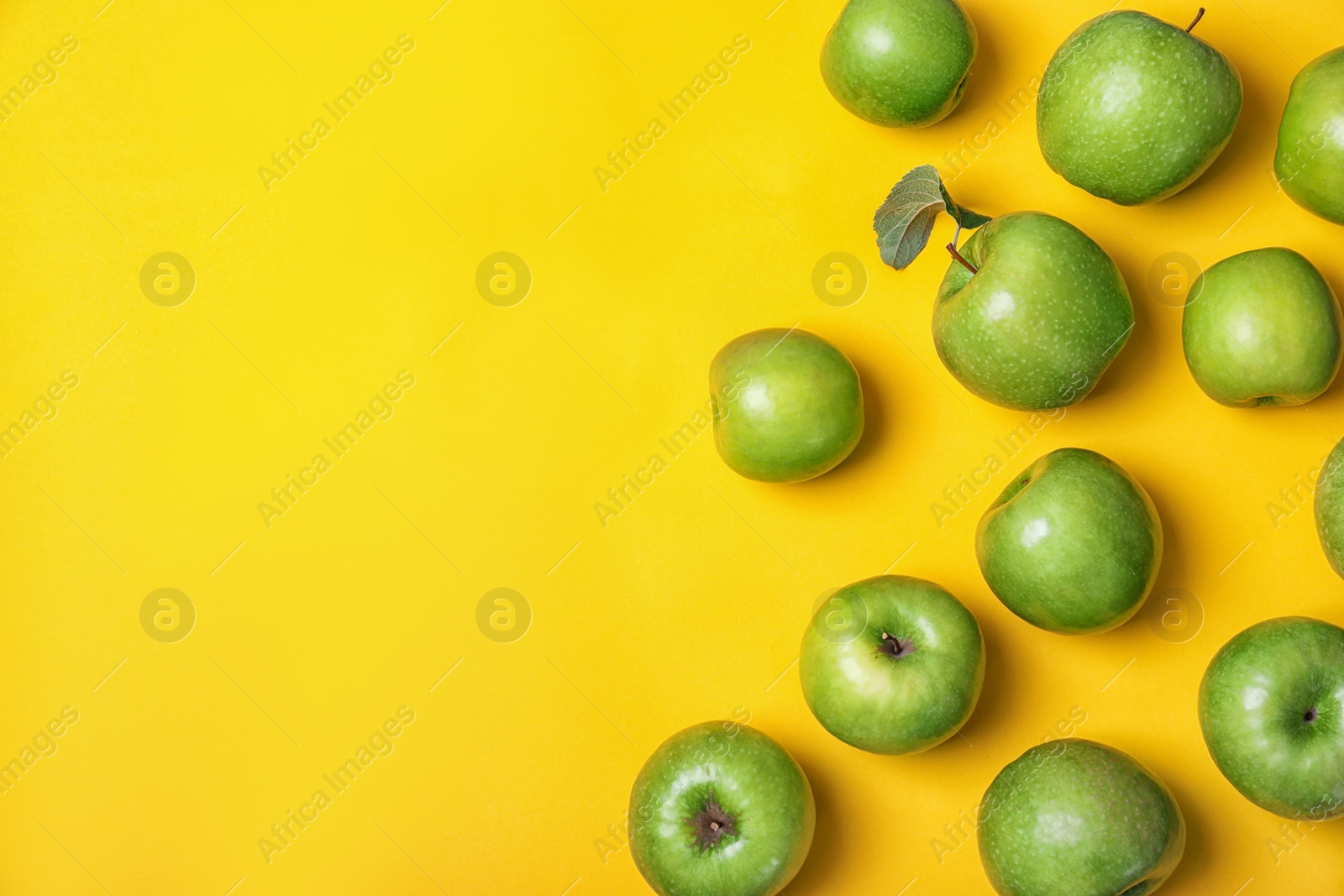 Photo of Many juicy green apples and space for text on color background, top view
