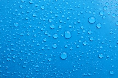 Water drops on light blue background, top view