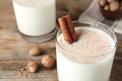 Photo of Milk with nutmegs and cinnamon on wooden table, closeup. Space for text
