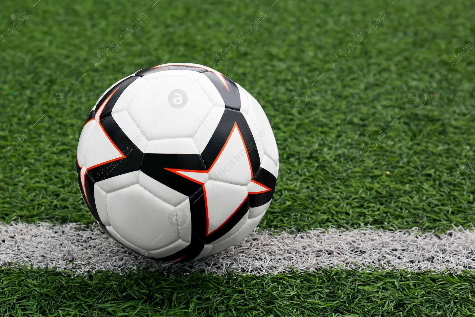 Photo of New soccer ball on green football field, space for text