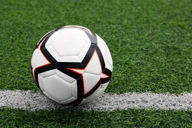 Photo of New soccer ball on green football field, space for text
