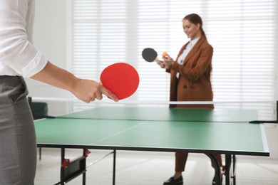 Photo of Business people playing ping pong in office, focus on tennis racket. Space for text