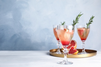 Glasses of grapefruit cocktails on table. Space for text