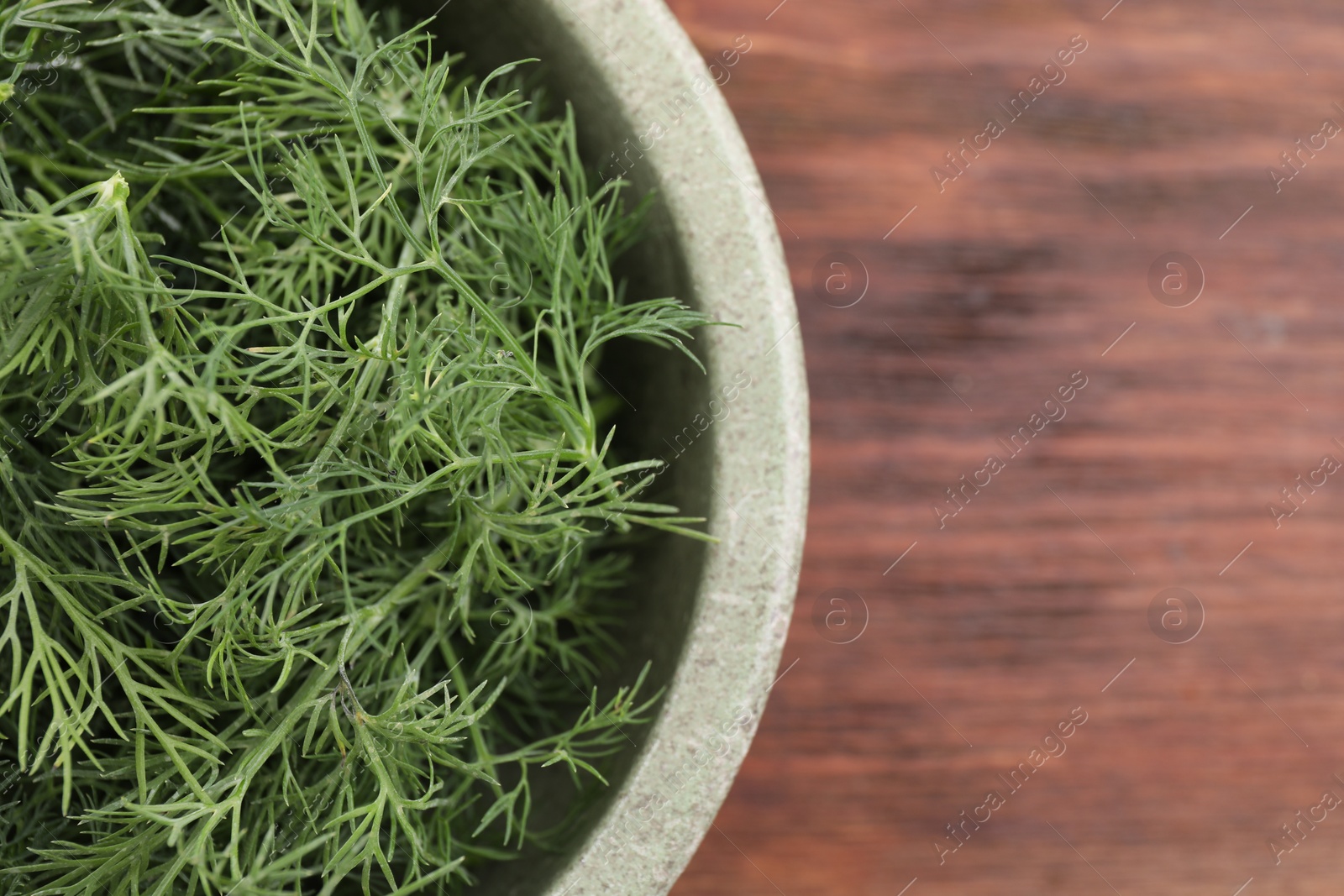 Photo of Bowl of fresh dill on wooden table, top view. Space for text