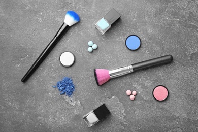 Flat lay composition with cosmetic products and makeup brushes on grey background