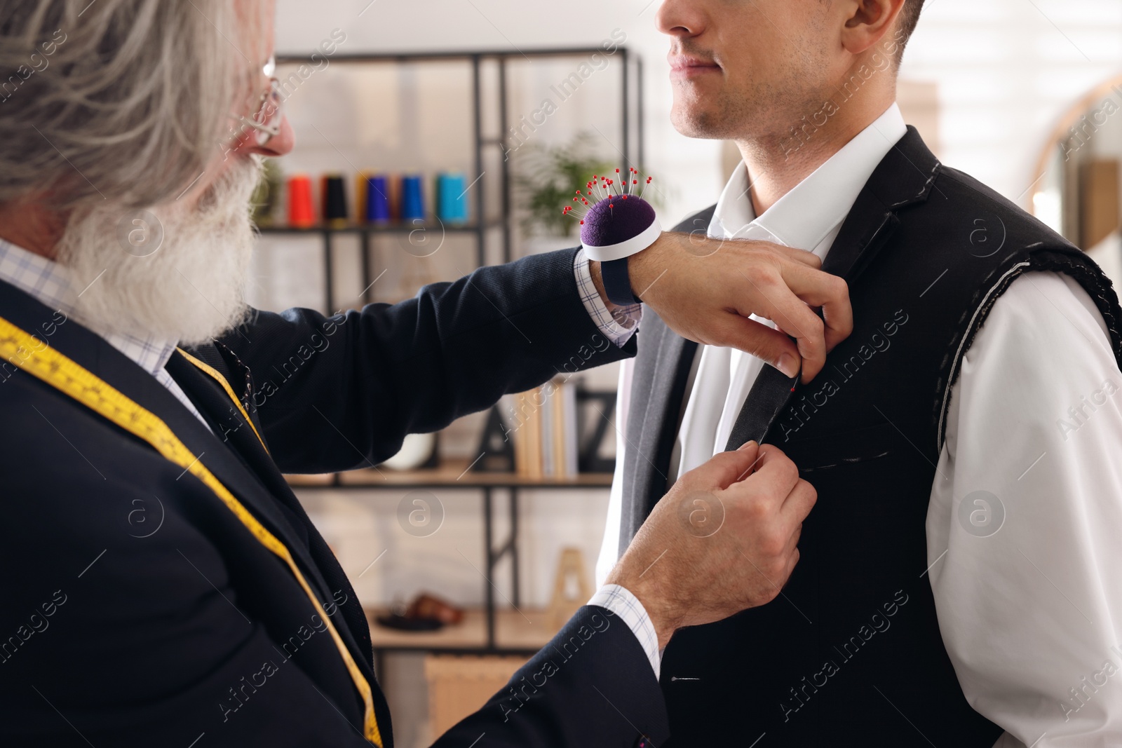 Photo of Professional tailor working with client in atelier, closeup