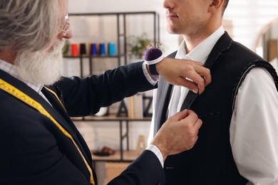 Professional tailor working with client in atelier, closeup