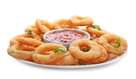 Photo of Plate with fried onion rings and bowl of sauce on white background