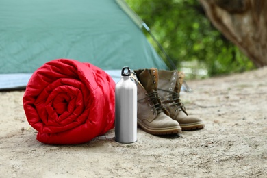 Rolled sleeping bag and other camping equipment outdoors