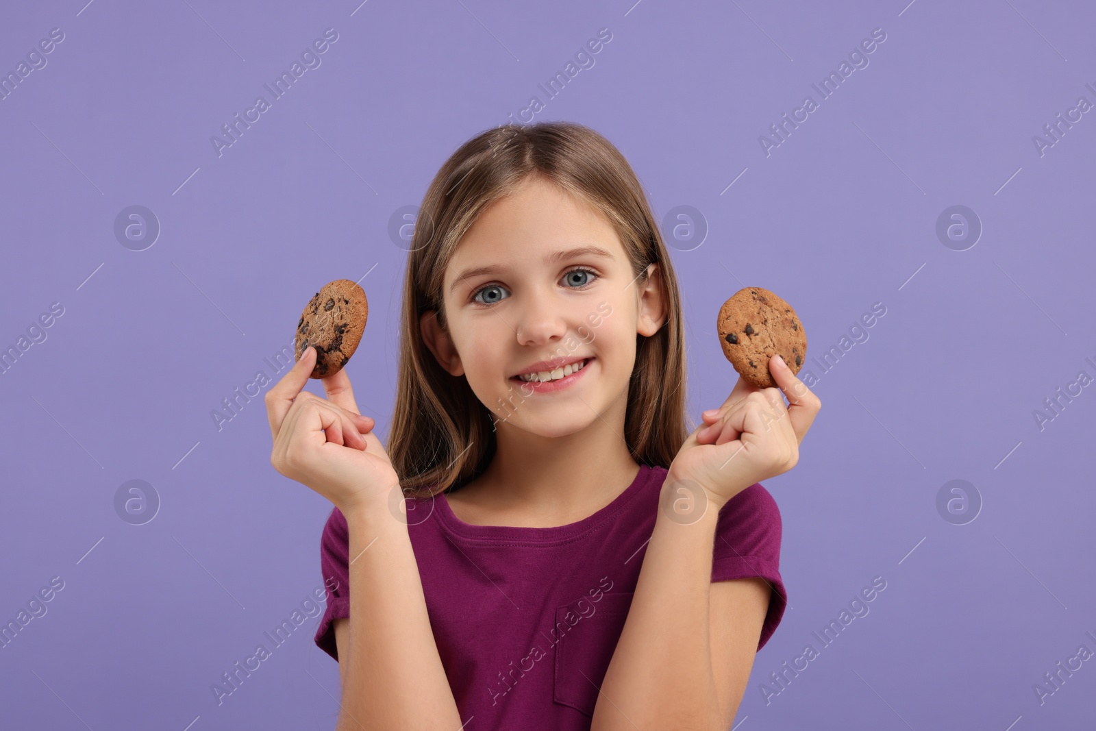 Photo of Cute girl with chocolate chip cookies on purple background