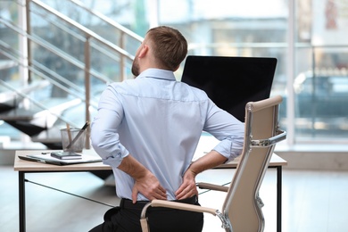 Photo of Businessman suffering from back pain at workplace