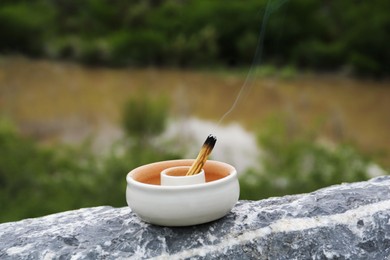 Burning palo santo stick on stone surface in high mountains