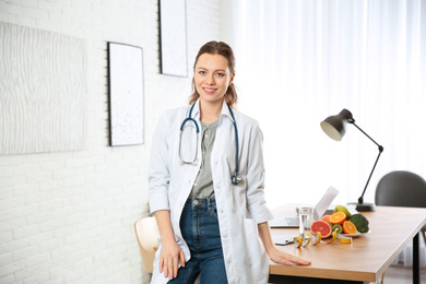 Nutritionist with stethoscope near desk in office