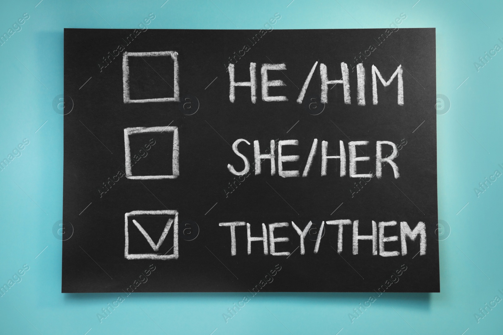 Photo of Blackboard with written pronouns on turquoise background, top view. Gender equality